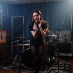 woman in black and white stripe shirt standing on black drum set