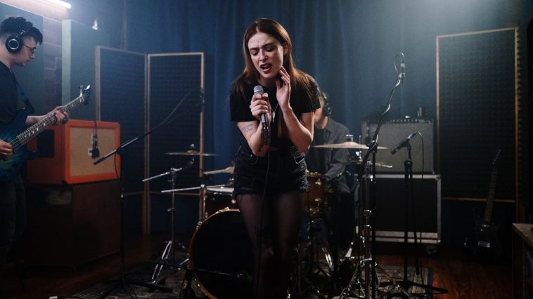 woman in black and white stripe shirt standing on black drum set