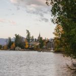 peaceful lake with residential cottages and lush trees on shore in autumn