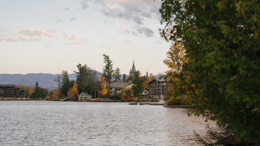 peaceful lake with residential cottages and lush trees on shore in autumn